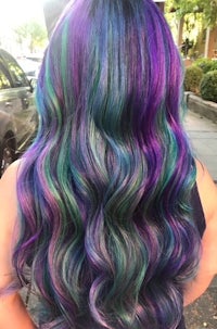 the back of a woman with long purple and green hair