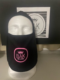 a black mask with a pink logo on it