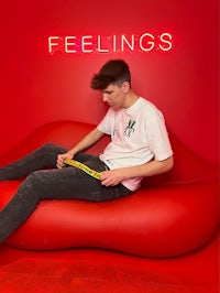 a man sitting on a red couch with the words feelings on it