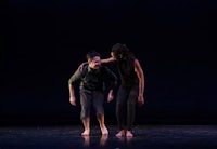 two dancers on stage in a dark room