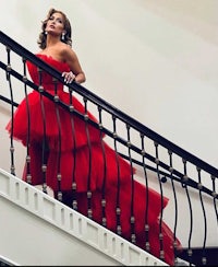 a woman in a red dress standing on a staircase