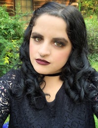 a woman with black hair and lipstick is posing for a photo