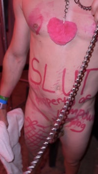 a naked man holding a chain with slut written on it