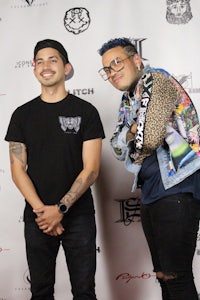 two men standing next to each other on a red carpet