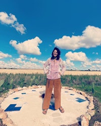 a woman standing in front of a circle in the middle of a field
