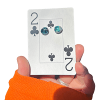 a person holding up a playing card with two studs on it