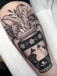 a black and white tattoo of cats in a vase