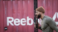 a man in a beanie is standing next to a reebok box