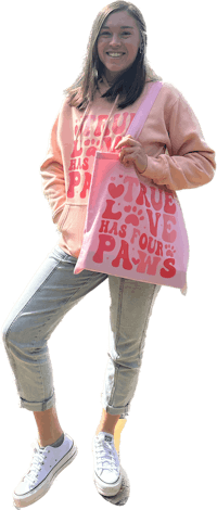a girl wearing a pink hoodie and jeans holding a pink tote bag
