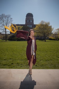 a woman in a graduation gown posing in front of a building