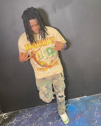 a man with dreadlocks and a camouflage t - shirt