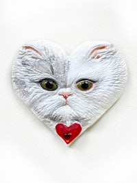 a white cat in a heart shape on a white wall