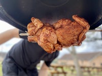 a man is preparing a chicken on a grill
