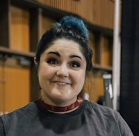 a woman with blue hair is smiling in front of a camera