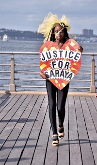 a woman holding a sign that says justice for sarah