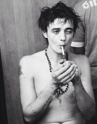 a shirtless man smoking a cigarette