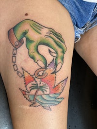 a woman's thigh with a tattoo of a hand holding a flower