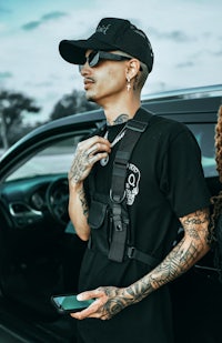 a man with tattoos standing next to a car