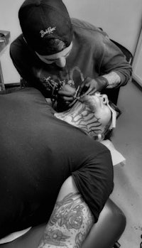 a man getting a tattoo on his neck