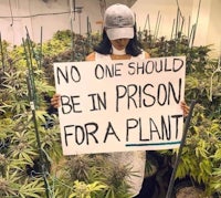 a woman holding a sign that says no one should be in prison for a plant