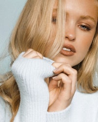 a blonde woman wearing a white sweater