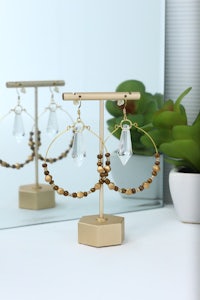 hoop earrings on a gold stand next to a plant