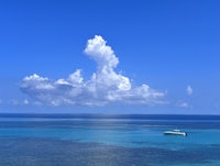 a boat is floating in the blue water near a cloudy sky