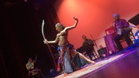 a belly dancer performs on stage with a sword