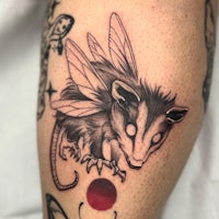 a tattoo of a possum with a red dot on it