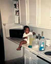 a baby sitting on a counter in a kitchen