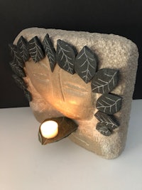 a stone candle holder with leaves on it