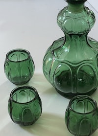 a green glass decanter set with three glasses