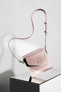 a pink cross body bag sitting on a table