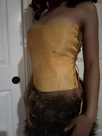 a woman is posing in a tan leather corset
