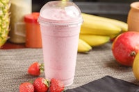 a pink smoothie with strawberries and bananas on a table