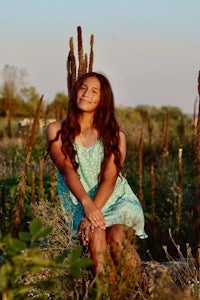 a girl in a blue dress sitting in a field