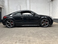 a black audi tt coupe parked in front of a brick building