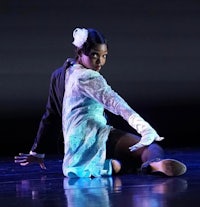 a female dancer in a white dress on a stage