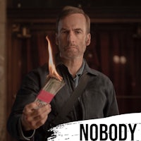 a man is holding a burning piece of paper with the word nobody on it