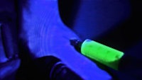 a person is holding a green glow stick in the dark