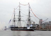 a large sailing ship is in the water near a city