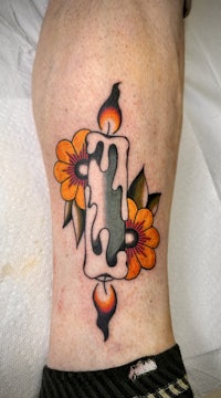 a tattoo of a candle and flowers on a person's leg