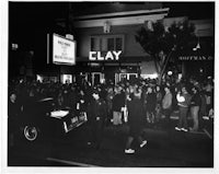 a black and white photograph of a crowd in front of a theater