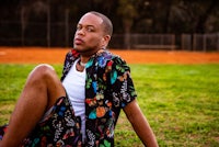 a man in a floral shirt sitting on the grass