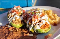 two stuffed avocados with rice and beans on a plate