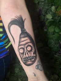 a tattoo of a skull with long hair on a person's forearm