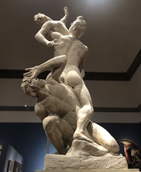 a statue of two men wrestling in a museum