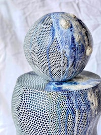 two blue and white ceramic spheres sitting on top of each other