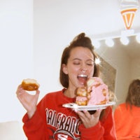 a woman in a red sweatshirt holding a plate of donuts