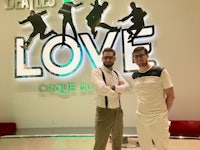 two men standing in front of a sign that says love circus du du